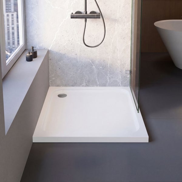 Moderne Badezimmerszene mit weißer rechteckiger Duschwanne, Glasduschwand, Wandfliesen in Marmoroptik und dunklem Boden.