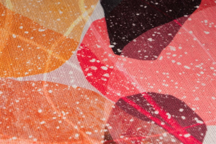 Nahaufnahme eines bunt gemusterten Textils mit abstrakten, sich überlagernden Kreisen und weißem Spritzmuster.