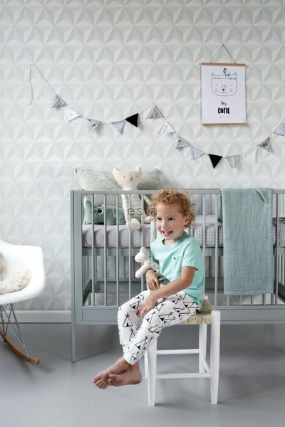 Helles Kinderzimmer mit Kinderbett, Dekoration und lachendem Kind