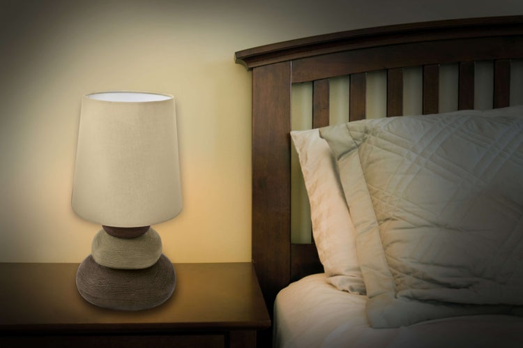 Nachttischlampe mit Stoffschirm neben einem Bett