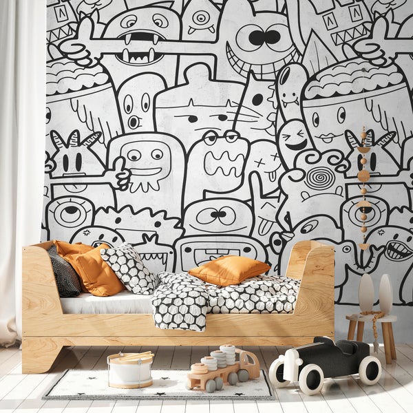 Helles Kinderzimmer mit großflächiger Vliestapete im schwarz-weißen Monster-Design, einem Holzbett mit gemusterter Bettwäsche und Holzspielzeugen.