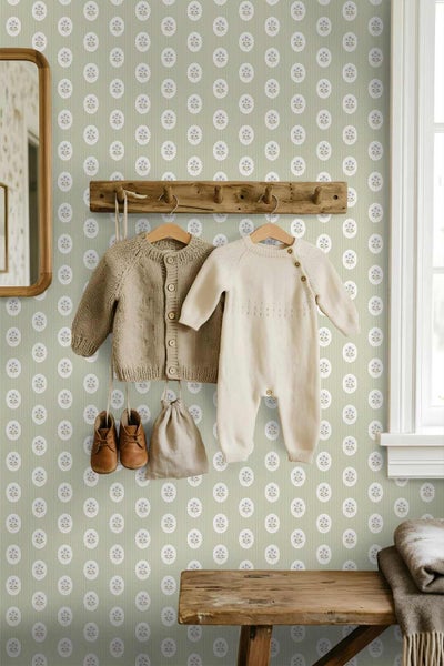 Kinderzimmer mit floral gemusterter Tapete, einer Holzgarderobe mit Kinderkleidung, Babyschuhen und einer Holzbank.
