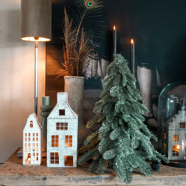Dekorative Szene mit beleuchteten Häusern, künstlichem Tannenbaum, Kerzen und Stehlampe auf einem Tisch