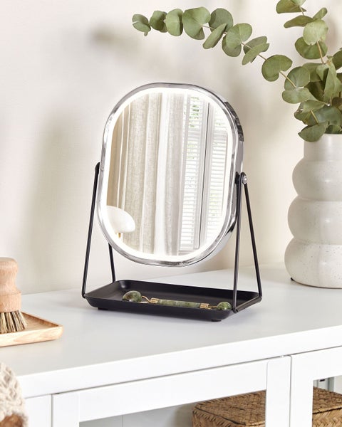 Beleuchteter Kosmetikspiegel auf einem weißen Tisch mit Dekoration