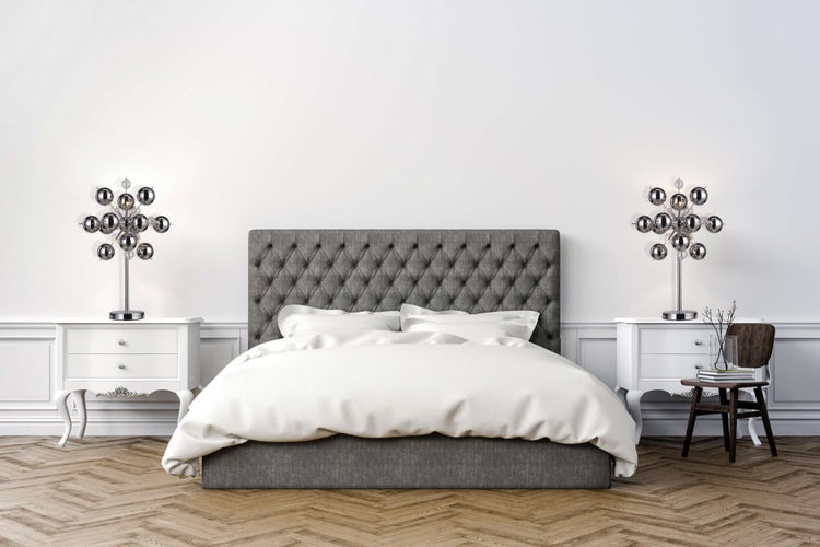 Helles Schlafzimmer mit grauem Bett, weißen Nachttischen und modernen Lampen