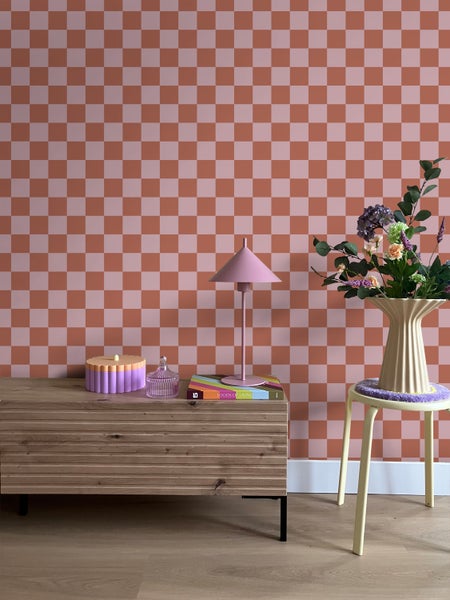 Innenraum mit Schachbrettmuster Tapete, Kommode, Lampe und Blumenarrangement