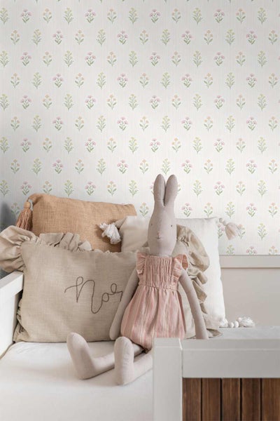 Vliestapete mit feinen Längsstreifen und kleinen Blumenmotiven in einem Kinderzimmer mit Kissen und Stofftier.