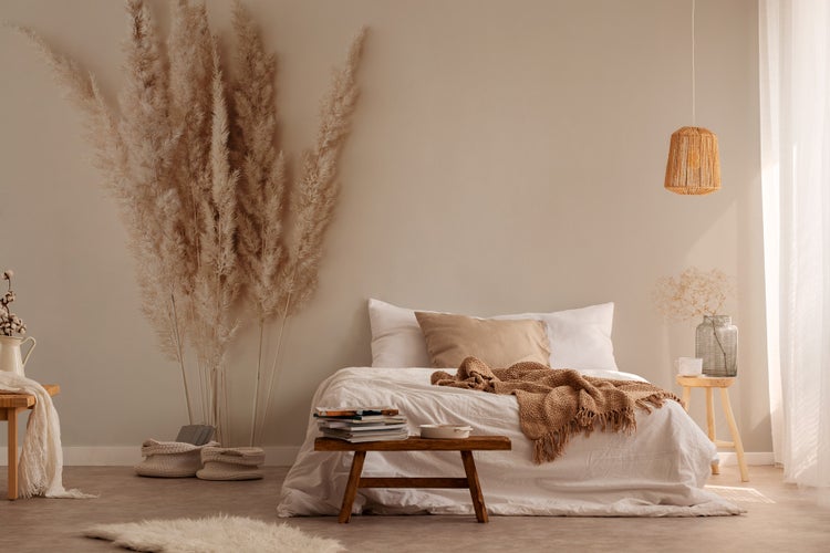 Helles Schlafzimmer mit Bett, Holzmöbeln und Dekorationen im Boho-Stil