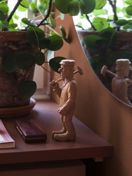 Dekorative Holzfigur eines Handwerkers mit Hammer auf einer Kommode