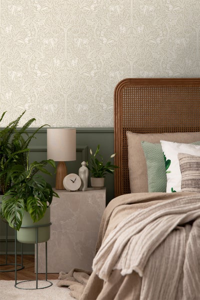 Schlafzimmer mit gemusterter Tapete, Bett mit Korbrahmen, Nachttisch und Zimmerpflanzen