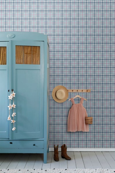 Karierte Tapete in Hellblau und Rosa in einem hellen Zimmer mit blauem Vintage-Schrank, hölzerner Hakenleiste und braunen Stiefeln.