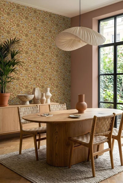 Modernes Esszimmer mit floraler Mustertapete, ovalem Holztisch, Flechtstühlen und großer Wellen-Pendelleuchte auf hellem Teppich.