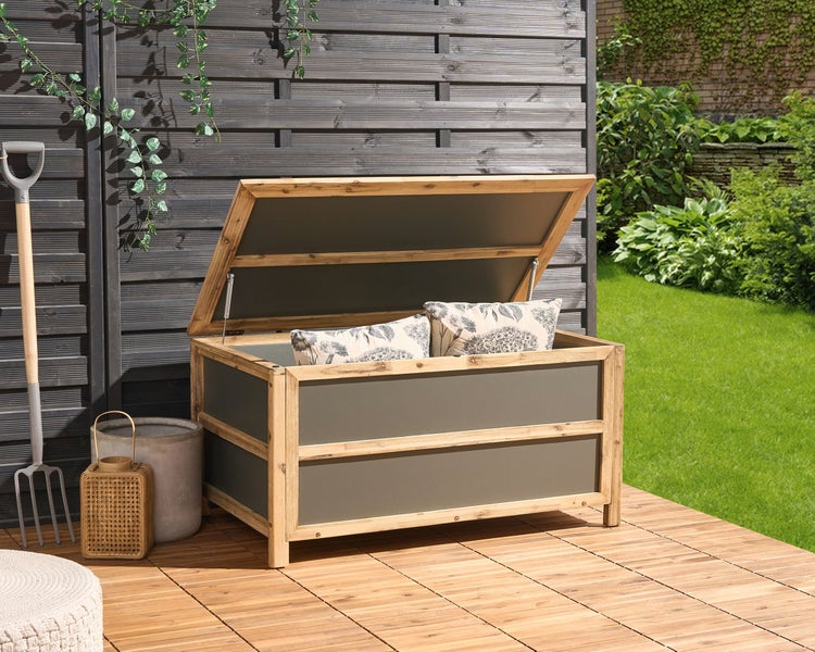 Geöffnete Gartenkissenbox aus Holz mit Kissen auf einer Holzterrasse