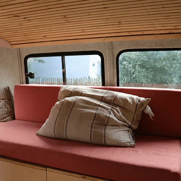 Innenraum eines Wohnmobils mit Sofa, Kissen und Holzdecke