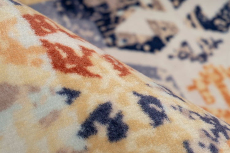 Detailaufnahme eines Teppichs mit geometrischem Muster und umgeschlagener Ecke zur Ansicht der Rückseite und Kantenverarbeitung.