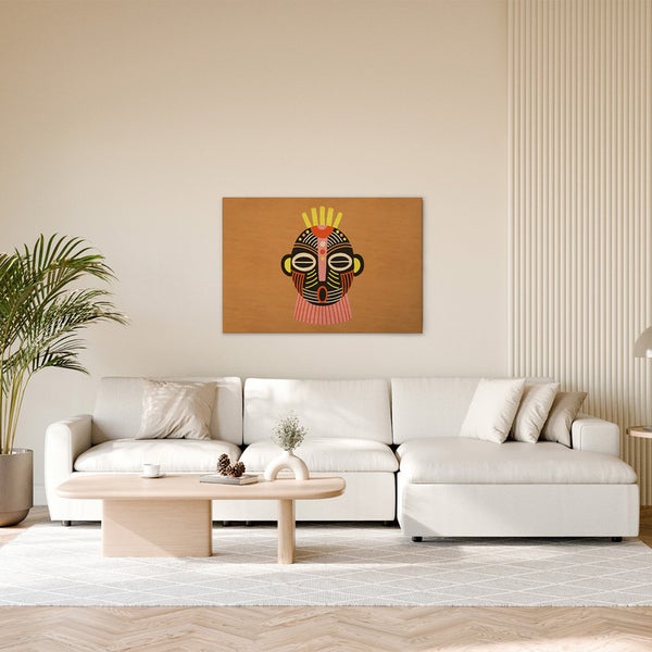 Dekoratives Wandbild mit einem afrikanisch inspirierten Maskenmotiv über einem hellen Sofa in einem Wohnzimmer.