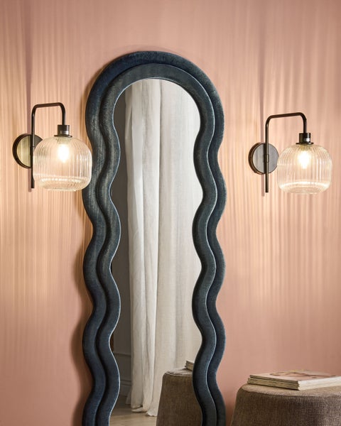 Dekorative Szene mit einem Spiegel mit gewelltem Rahmen und zwei Wandleuchten