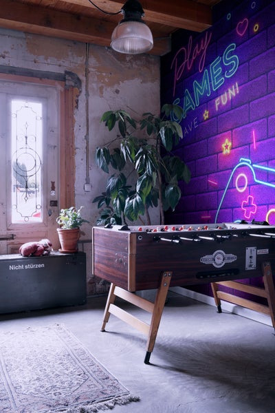 Interieuransicht eines Raumes mit Tischfußball, Pflanze und dekorativer Wand