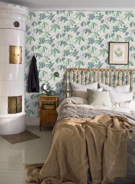 Schlafzimmer mit floraler Tapete, Bett und geöffneter Tür.