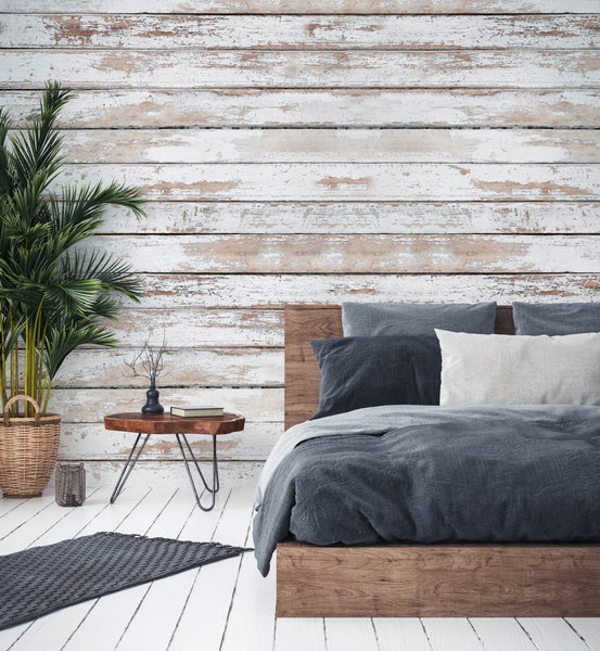 Schlafzimmer mit Wand in rustikaler Holzoptik, weiß gewaschene Holzplanken, Holzbett und Zimmerpflanze.