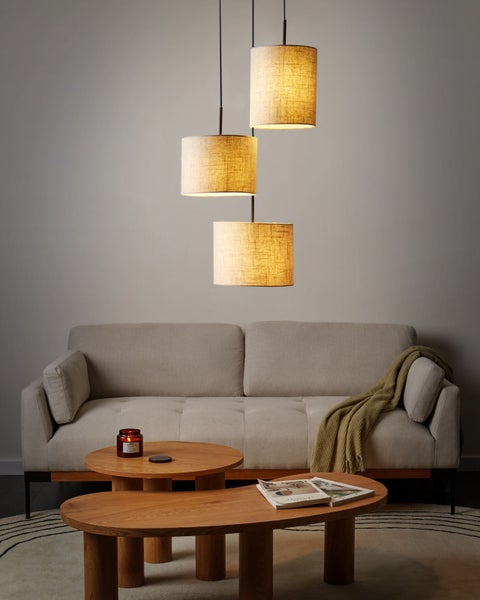 Wohnzimmer mit Stoff-Hängeleuchte, Couch und Holztischen