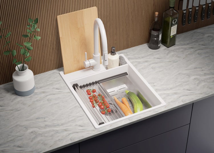 Küchenspüle mit Abtropfgestell, Armatur, Schneidebrett und Lebensmitteln auf einer Küchentheke.
