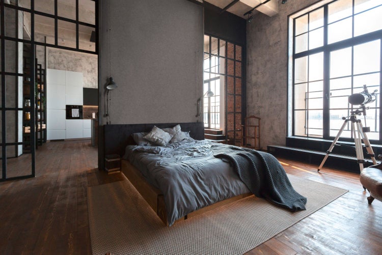 Helles Schlafzimmer mit Holzbett, Tisch, Pflanze und Teppich