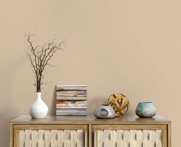 Dekorierte Holzkommode mit weißer Vase, Trockenzweigen, quadratischem Holzbild und modernen Deko-Elementen aus Keramik und Metall.