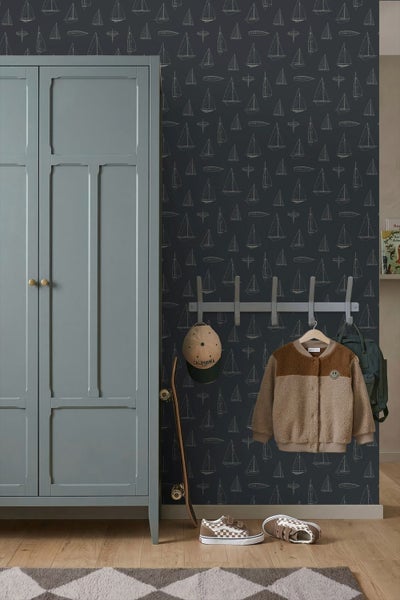 Vliestapete mit Segelboot-Motiv in einem organisierten Kinderzimmer neben einem Kleiderschrank und einer Garderobe.