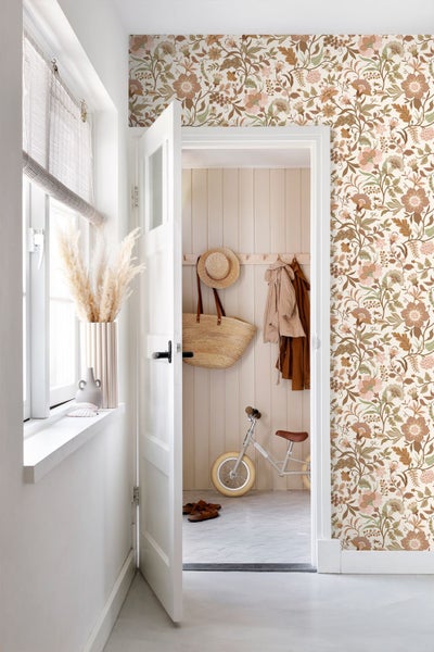 Vliestapete mit floralem Vintage-Muster an einer Wand in einem hellen Flur mit Garderobe aus Holz, Beistelltisch und Dekoration.