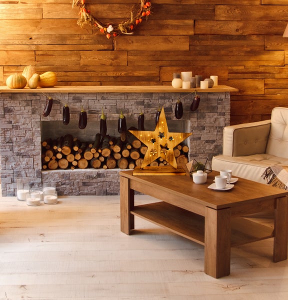 Dekoratives Wohnzimmer mit Kamin, Holzwand, Couch, Holztisch und Holzstern