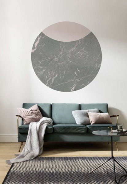 Wohnzimmer mit grünem Sofa, Kissen und runder Wanddekoration