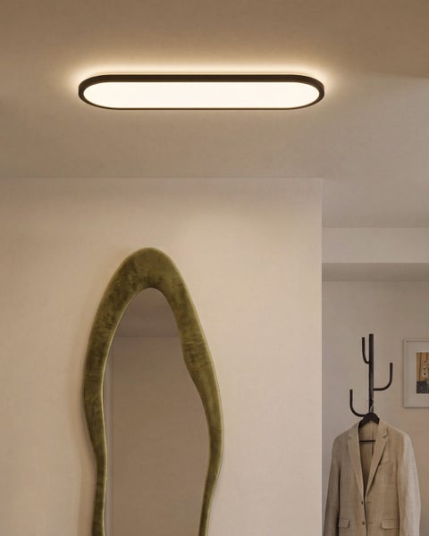Moderne ovale Deckenleuchte mit Rahmen und leuchtender Fläche im modernen Wohnflur mit geschwungenem Spiegel und Garderobe.