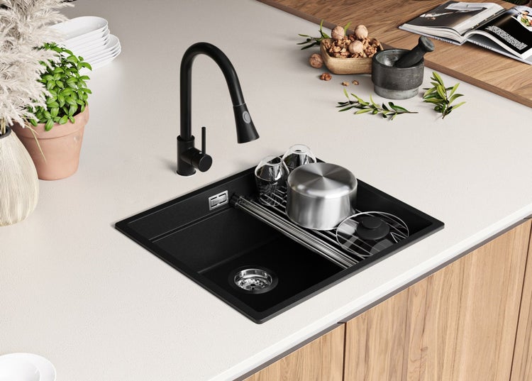 Schwarze Küchenspüle mit schwarzem Wasserhahn und Geschirr