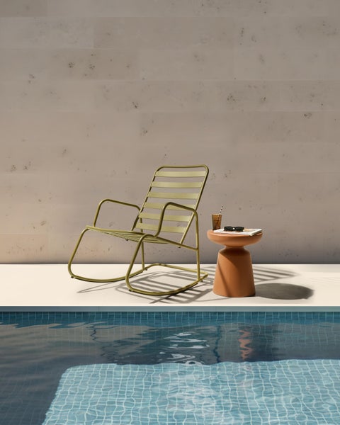 Szene mit einem grünen Schaukelstuhl aus Metall und einem Beistelltisch am Pool
