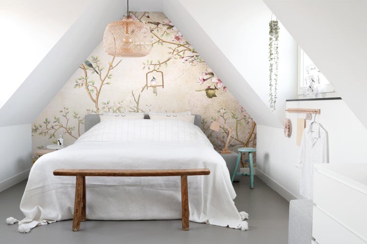 Schlafzimmer im Dachgeschoss mit Bett, Bank, Lampe und Vogelmuster-Tapete
