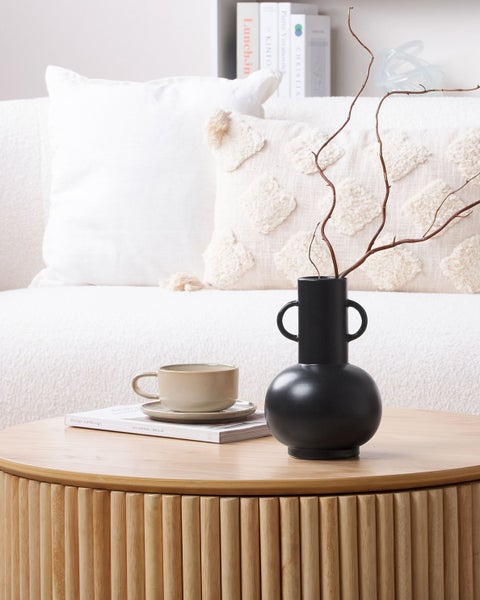 Dekorative Szene mit Couch, Zierkissen, Tisch, Tasse und Vase