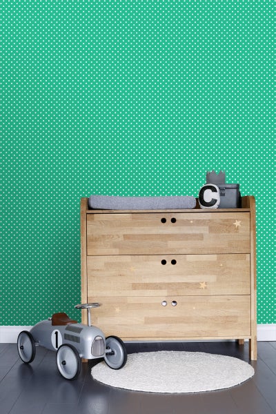 Helles Kinderzimmer mit Wickelkommode, Spielzeugauto und gemusterter Tapete
