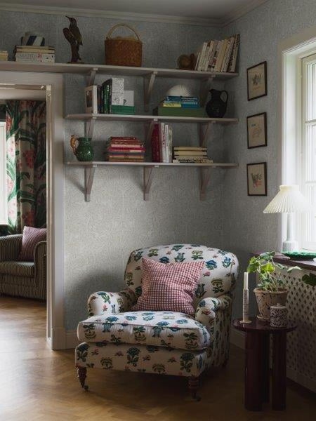 Wohnzimmer mit Sessel, Regalen und Dekorationen für eine gemütliche Atmosphäre