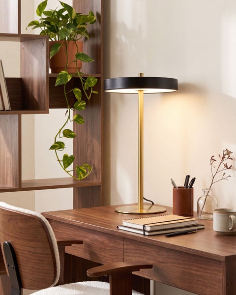 Moderne Schreibtischlampe mit rundem Lampenschirm auf einem Holztisch in einem stilvollen Arbeitszimmer