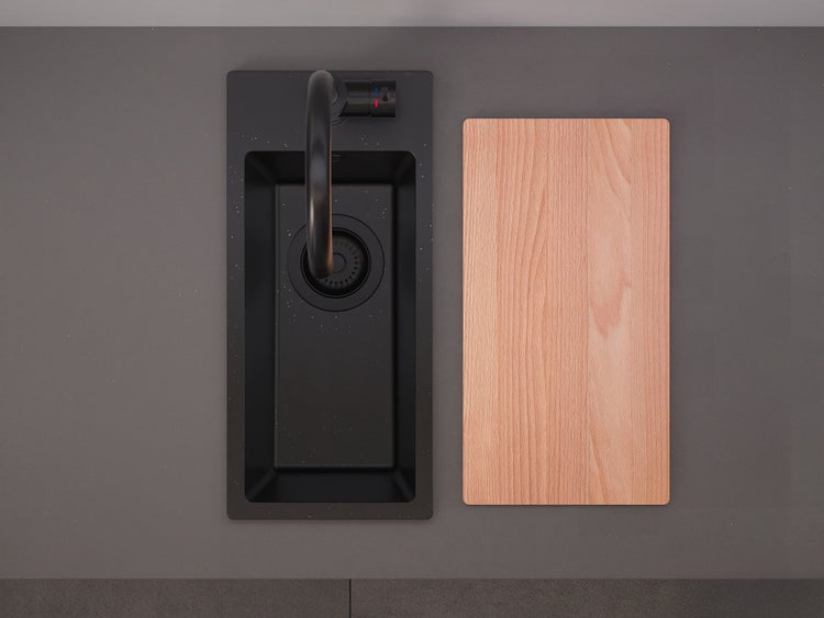 Schwarze Einbauspüle mit Armatur und einem Schneidebrett aus Holz auf einer Arbeitsplatte.