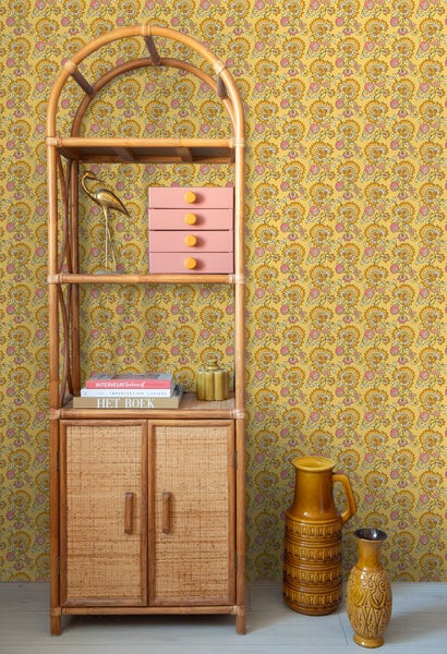 Szene mit Rattanregal, Kommode, Dekoration und gemusterter Tapete für ein stilvolles Interieur