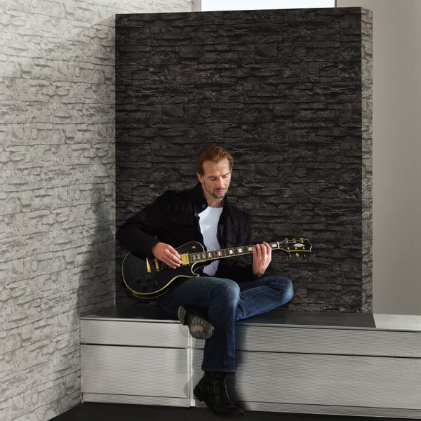 Dekorative Steinoptik Tapete im Innenraum mit Pflanze und Büchern.