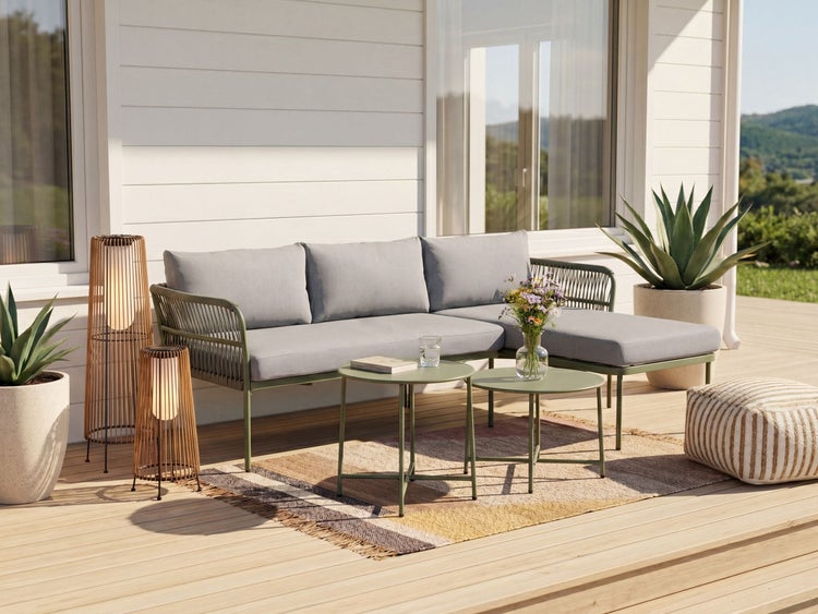 Moderne Gartenlounge auf einer Holzterrasse mit grauem Ecksofa, zwei grünen Beistelltischen, Gartenleuchten, Pflanzkübeln und einem Pouf.