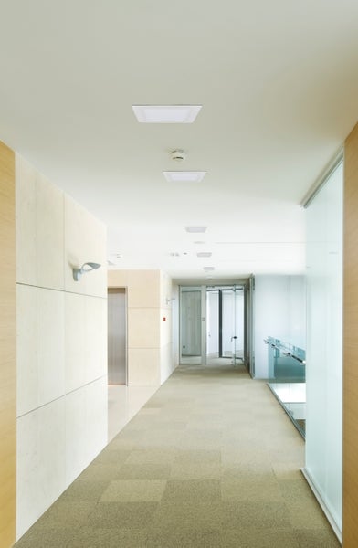 Innenaufnahme eines hellen Büroflurs mit quadratischen Deckenleuchten