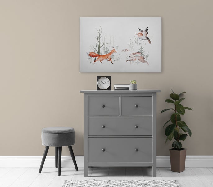 Wandbild mit Waldtiermotiven im Kinderzimmer über einer grauen Kommode mit Hocker und Pflanze.