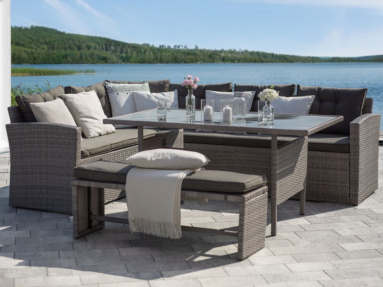 Graue Rattan-Gartenmöbel-Gruppe mit Tisch, Ecksofa und Bank auf Terrasse am See