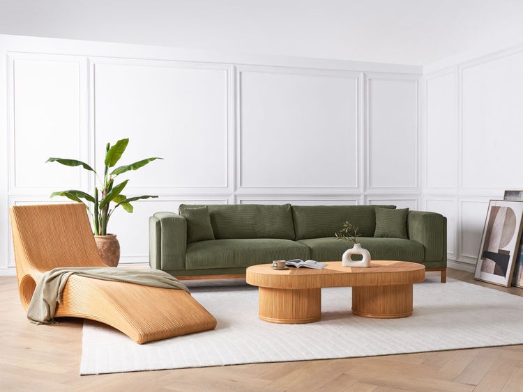 Wohnzimmer mit Sofa, Sessel, Couchtisch, Zimmerpflanze und Teppich