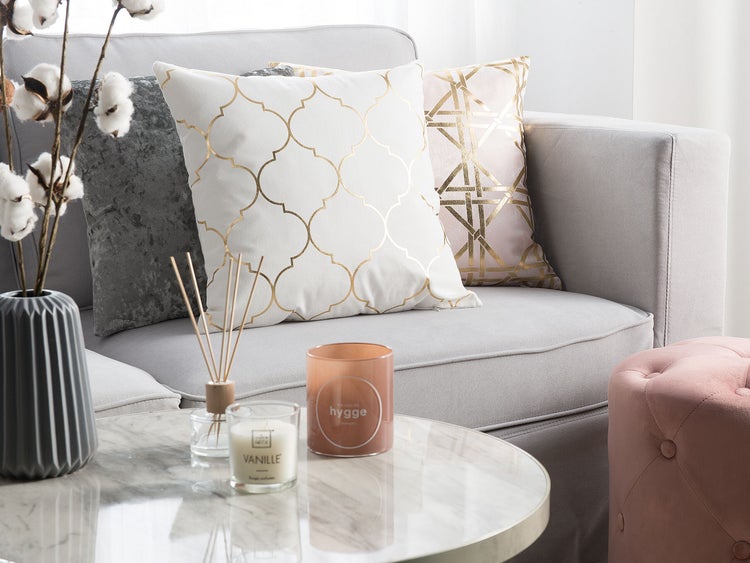 Dekorative Inneneinrichtung mit Kissen, Kerzen und Dekoration auf einem Couchtisch neben einem Sofa.