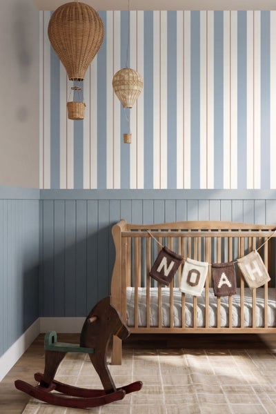 Kinderzimmer mit gestreifter Tapete in Blau, Weiß und Rot, einem Hausbett mit karierter Bettwäsche und einem blau-grauen Nachttisch.
